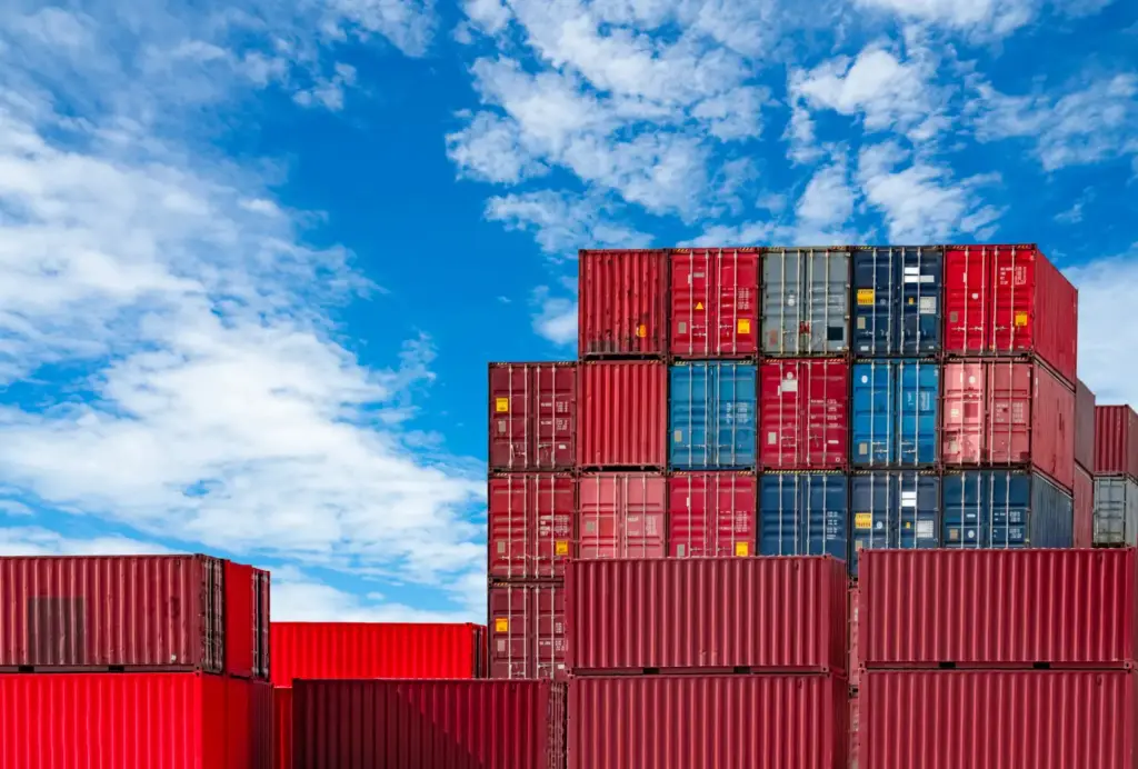 Contêineres empilhados no pátio de um terminal portuário, representando o acúmulo de custos de demurrage na importação por falta de controle no prazo de devolução.